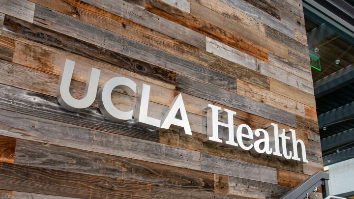 UCLA Health sign mounted on a weathered wooden plank wall exterior.